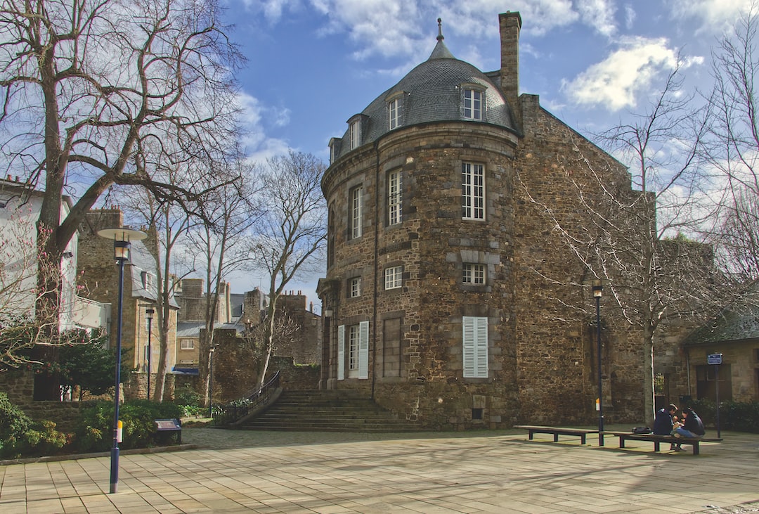 two people sitting on a bench in front of a building