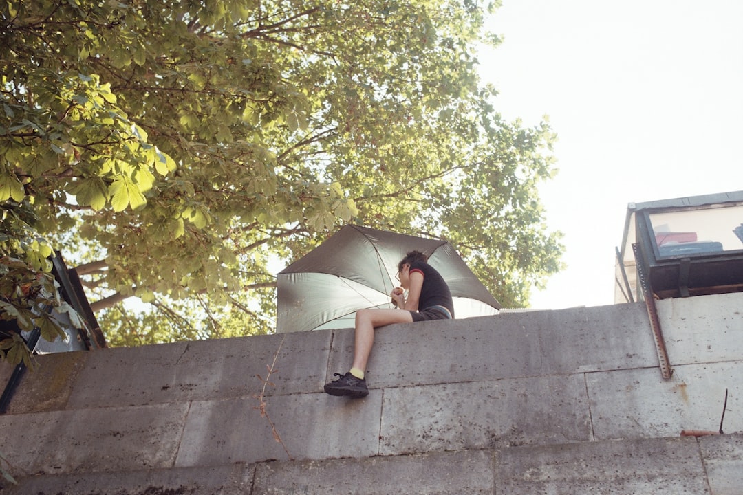 a person sitting on a ledge with an umbrella