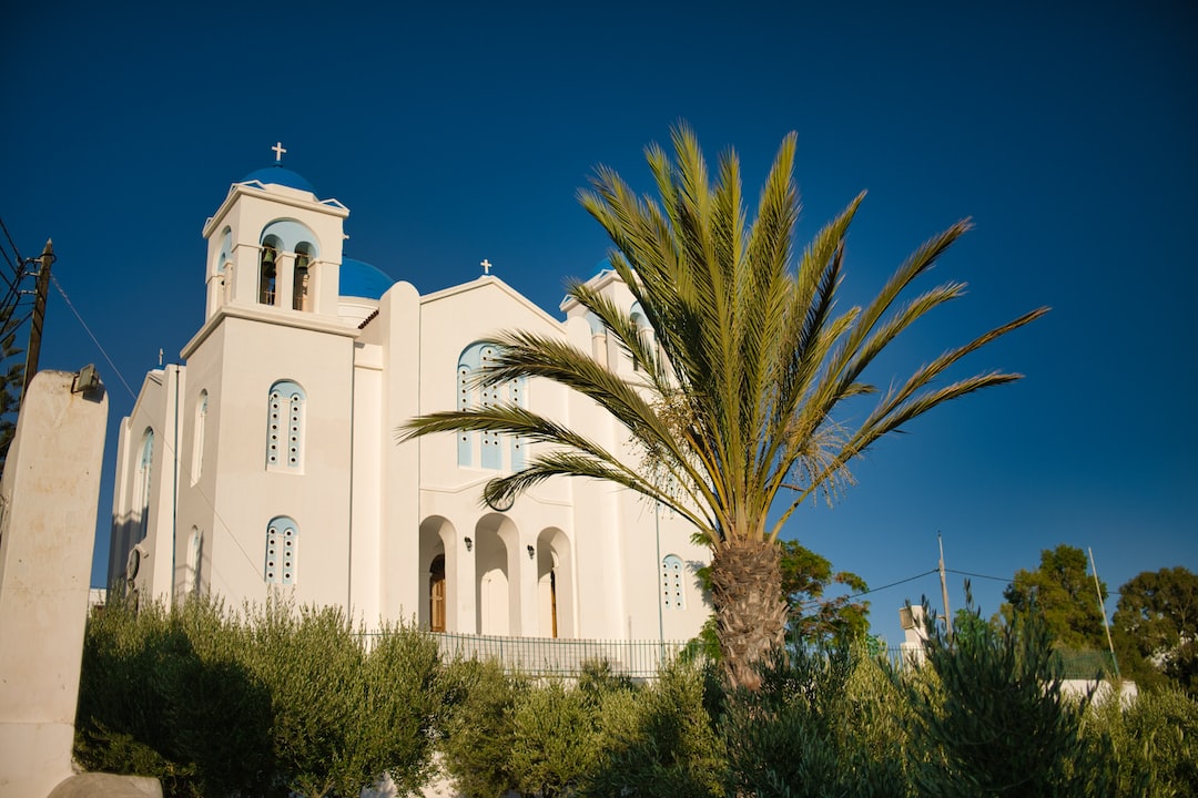 white concrete building near green trees under blue sky during daytime