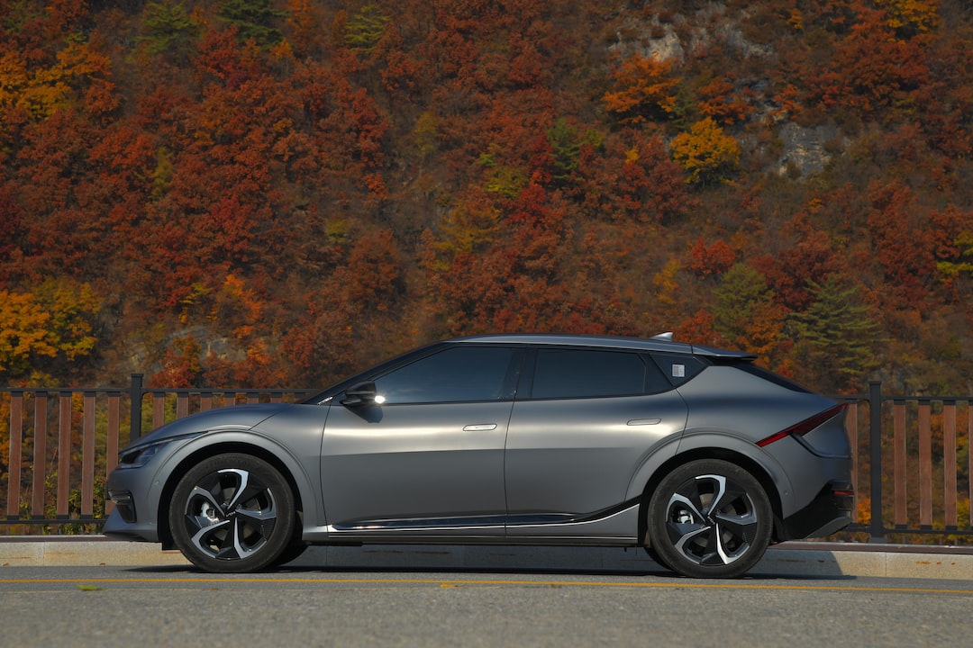 a silver car parked on the side of a road with trees in the background