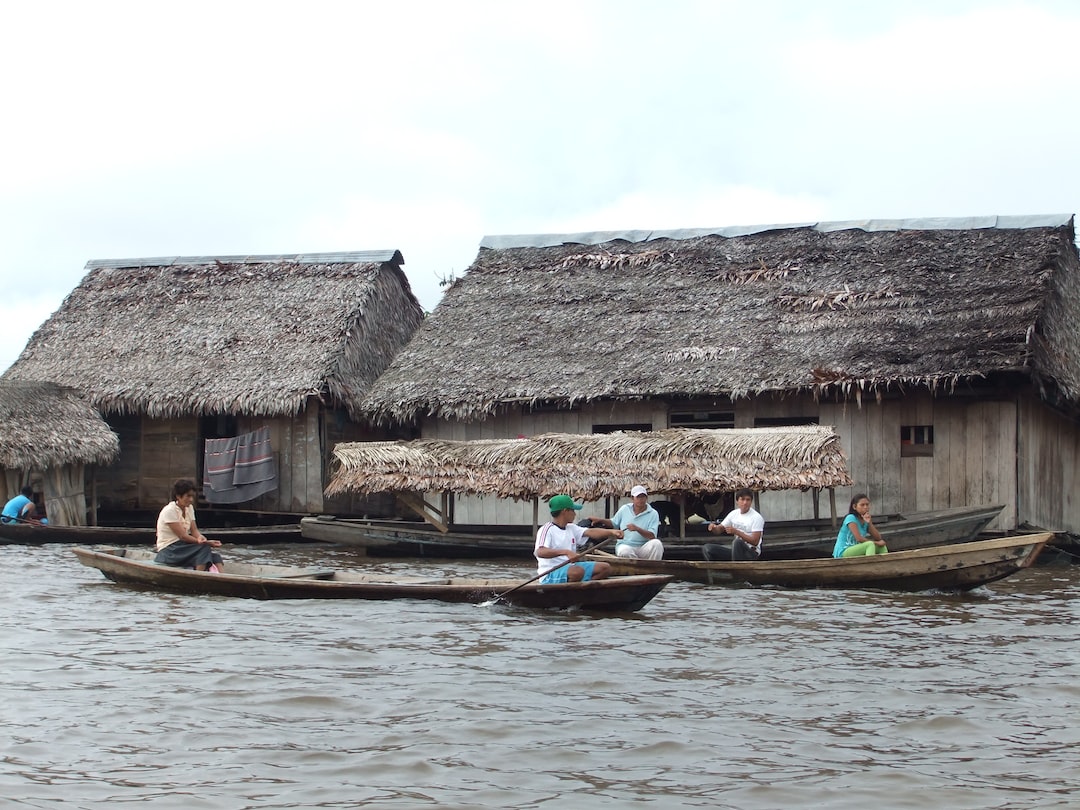 people riding on boat near brown wooden house during daytime