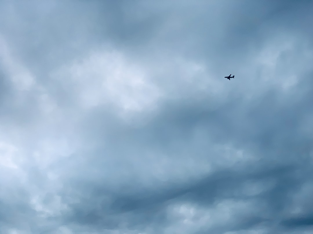 airplane flying under cloudy sky during daytime