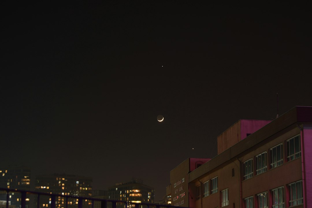 a view of a city at night with the moon in the sky