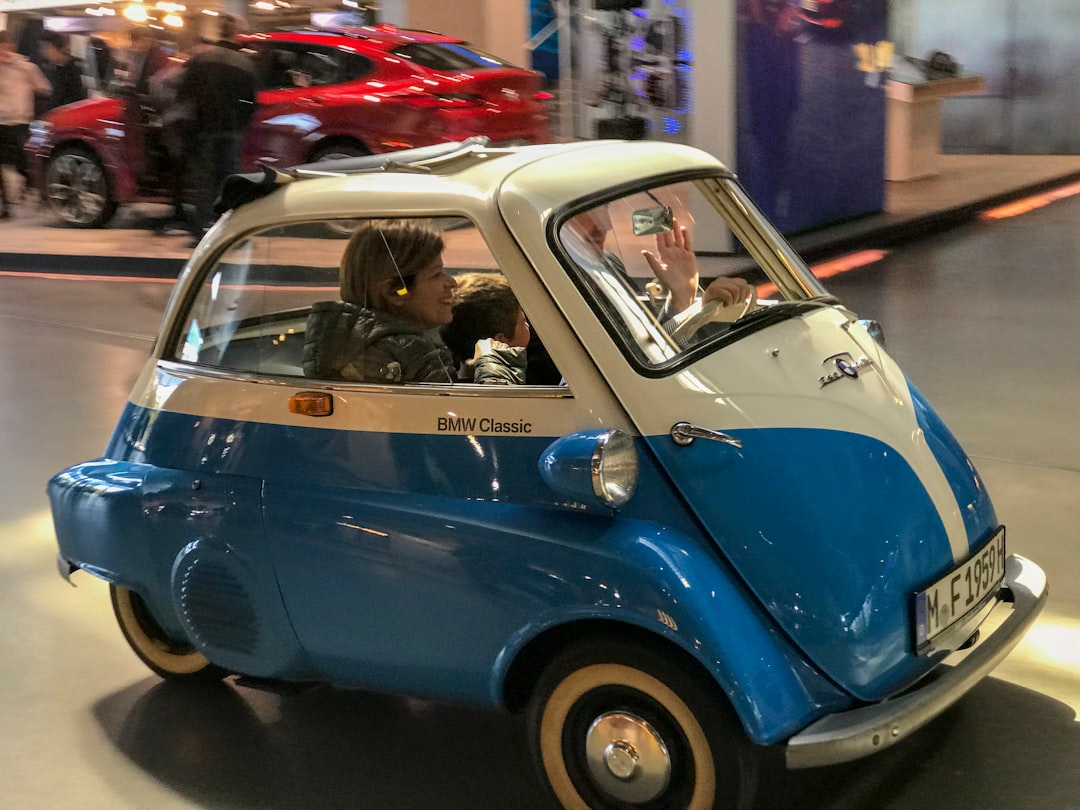 a small blue and white car driving down a street