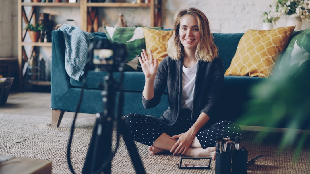 Woman waving hello at camera in living room.